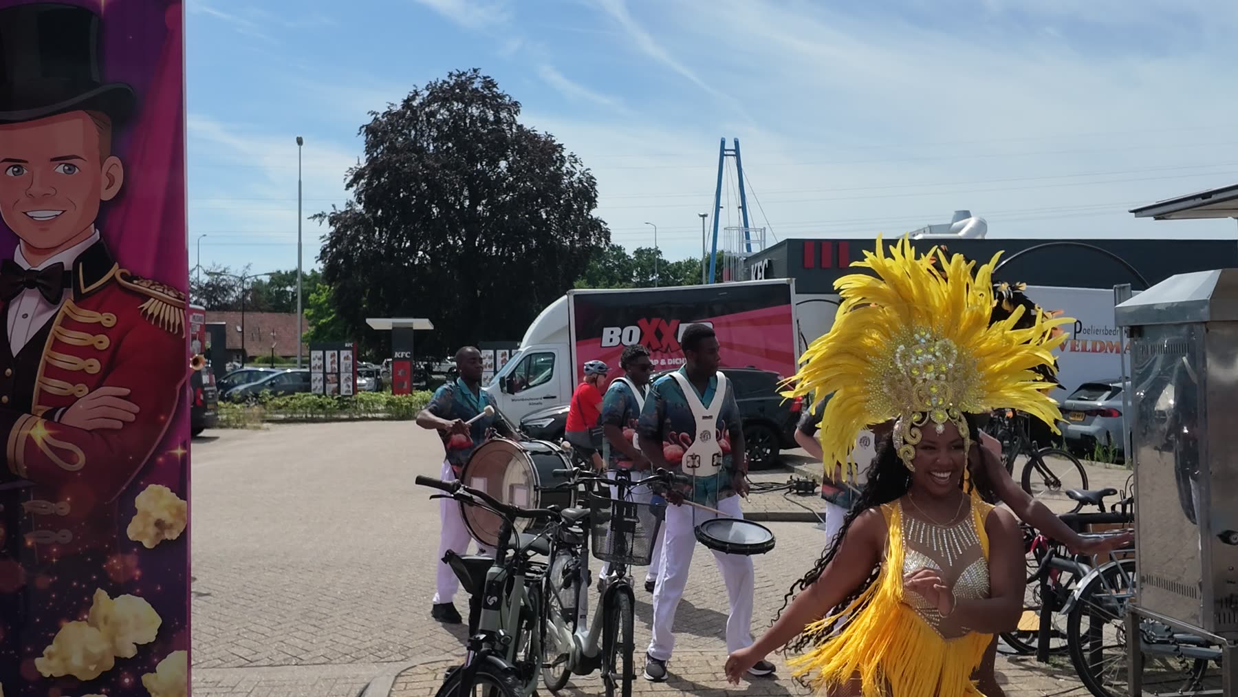 All In 1 drumband met danseres in geel verenkostuum tijdens een optreden buiten